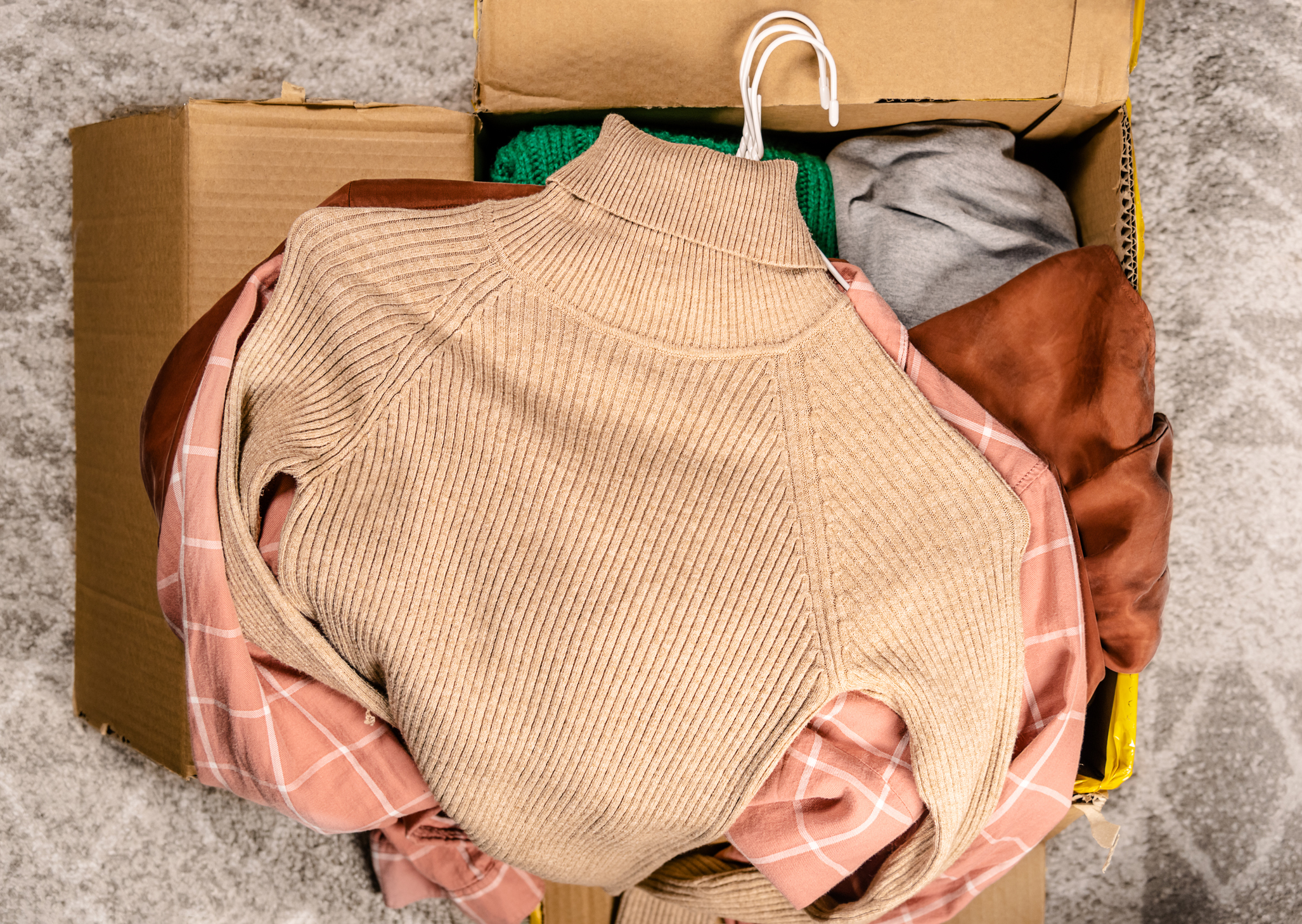 Clothes piled into a cardboard box