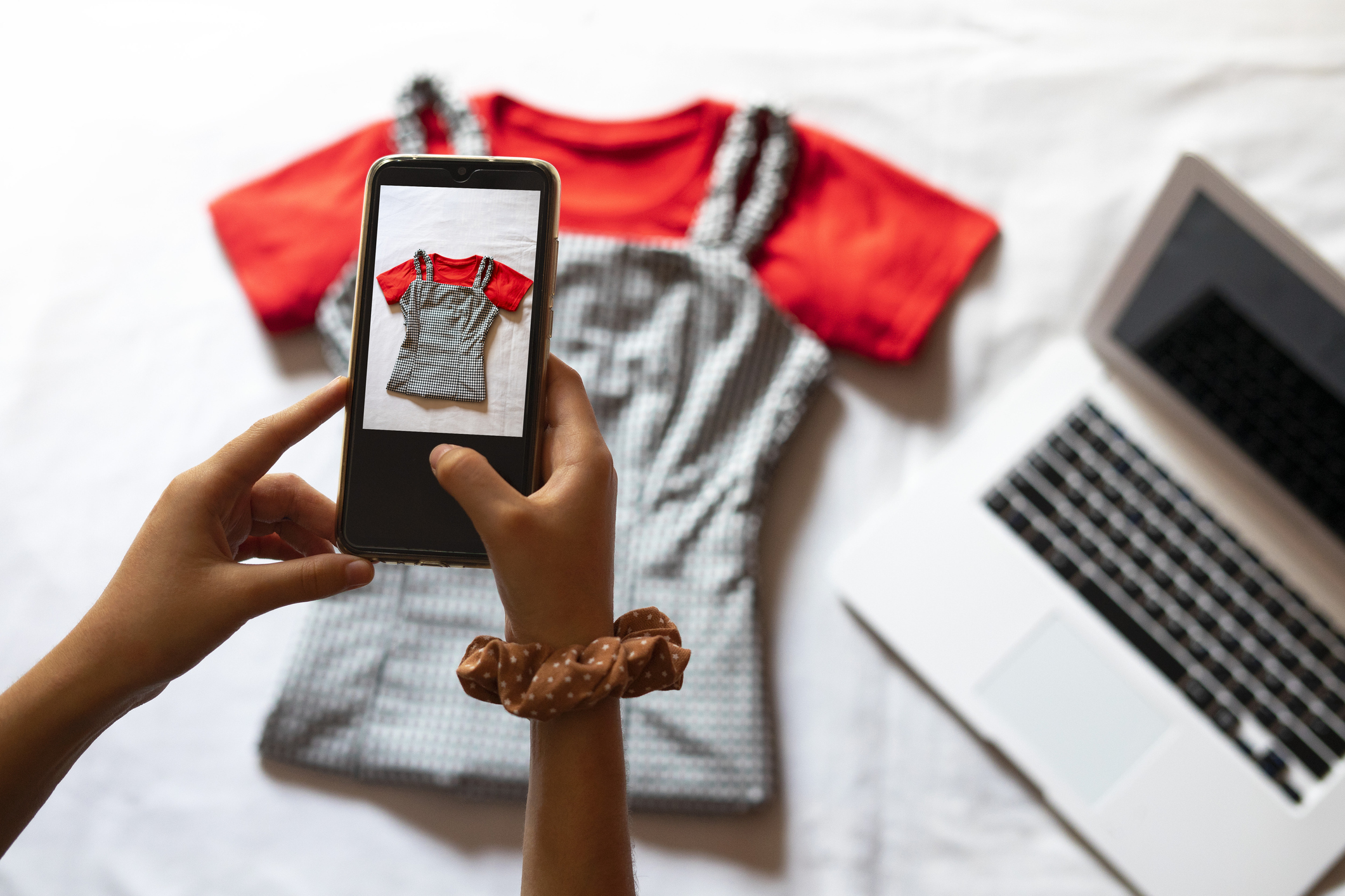 Lady taking a picture of a top to sell on phone