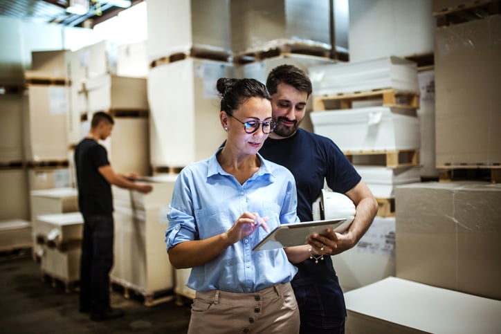 two-people-looking-at-tablet-in-stock-room