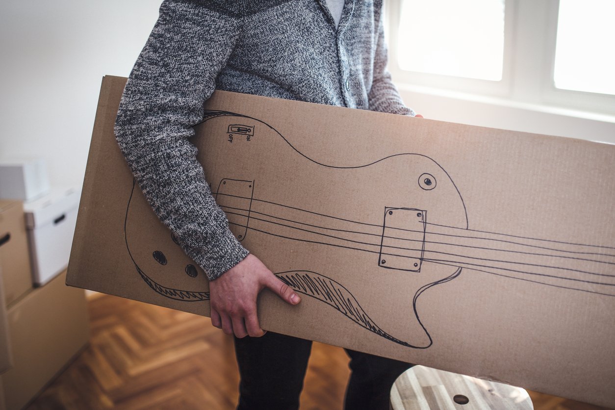 Man carrying box with drawing of a guitar on it