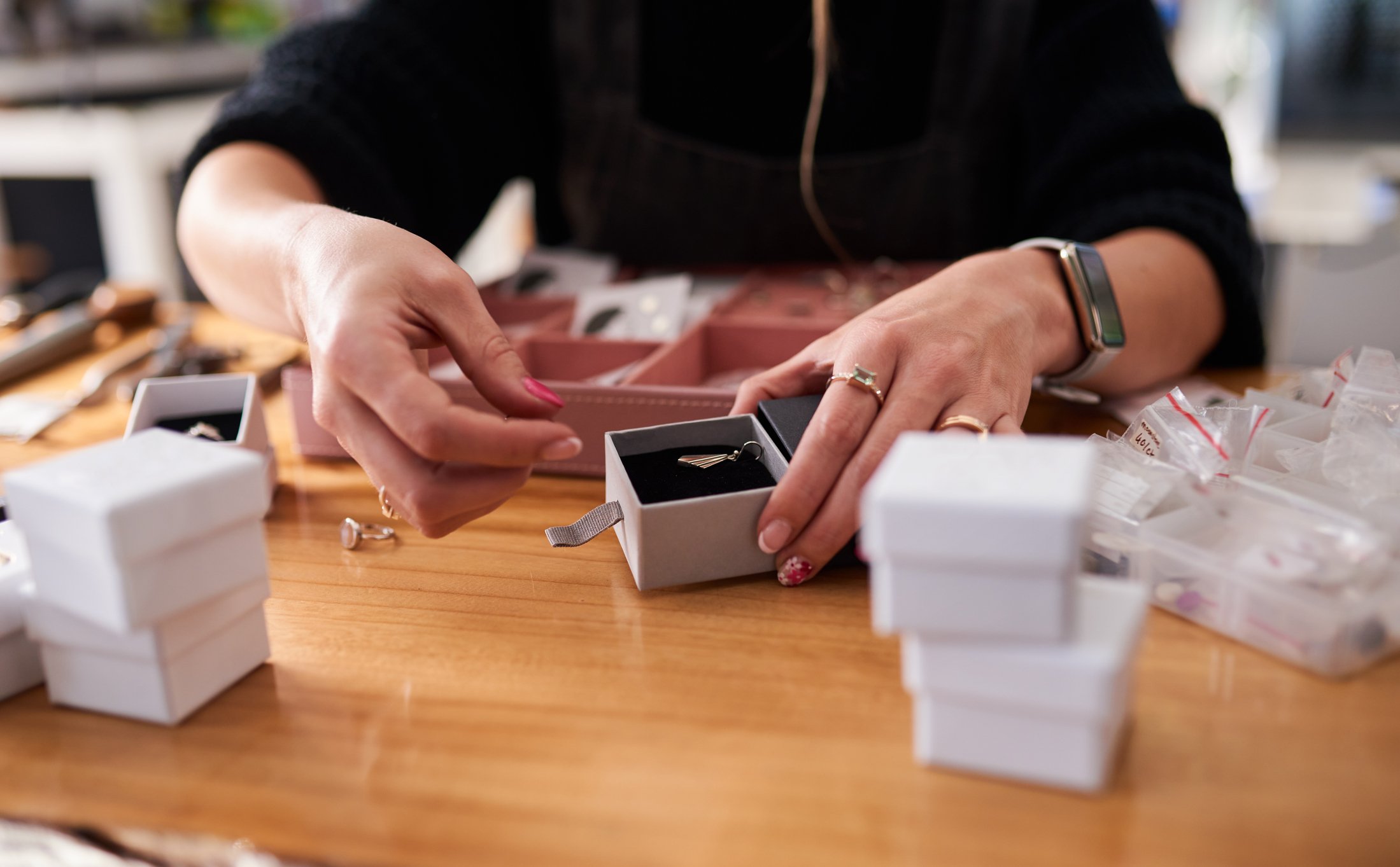 Woman putting jewellery into small jewellery boxes