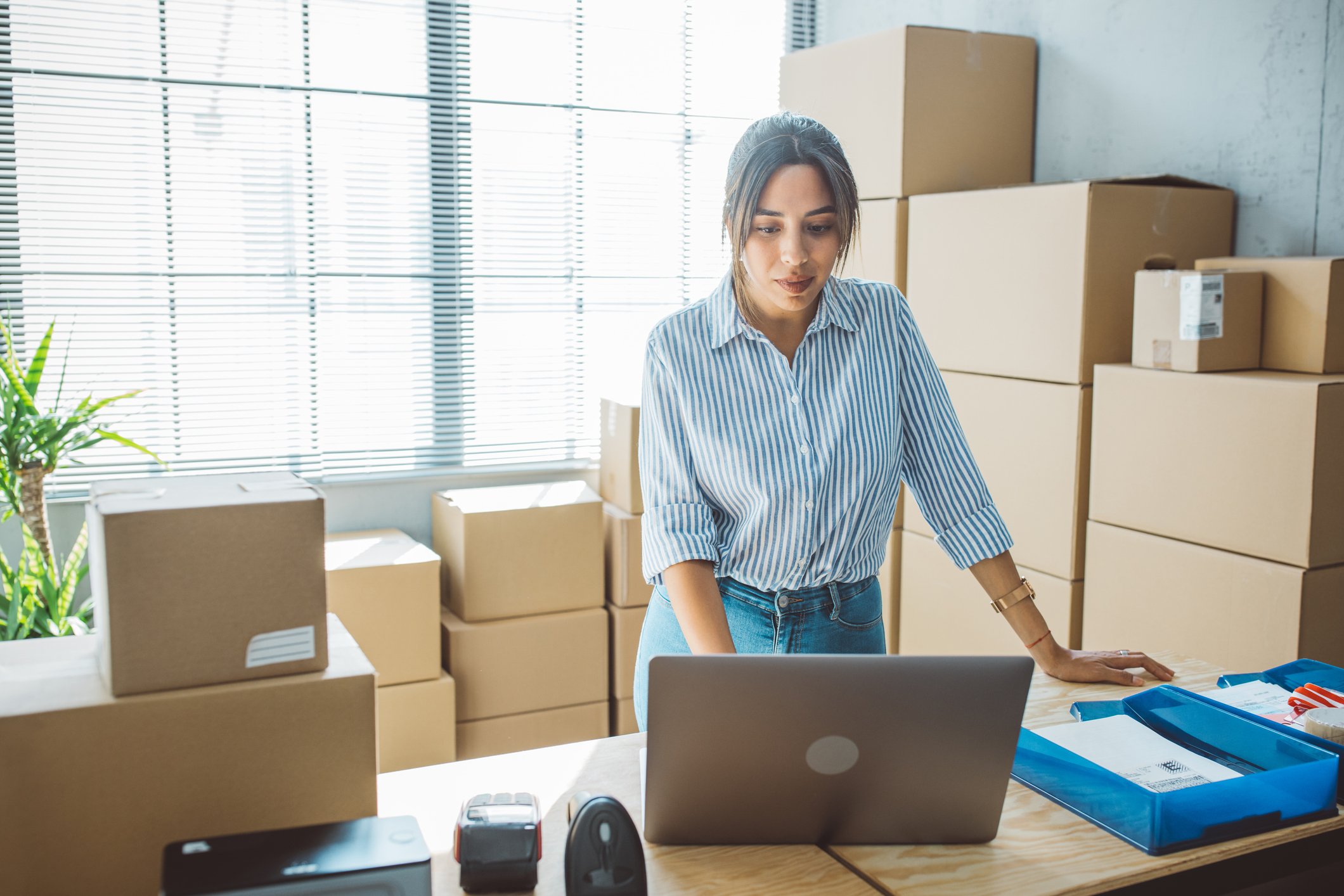 business woman using laptop with parcel storage in background