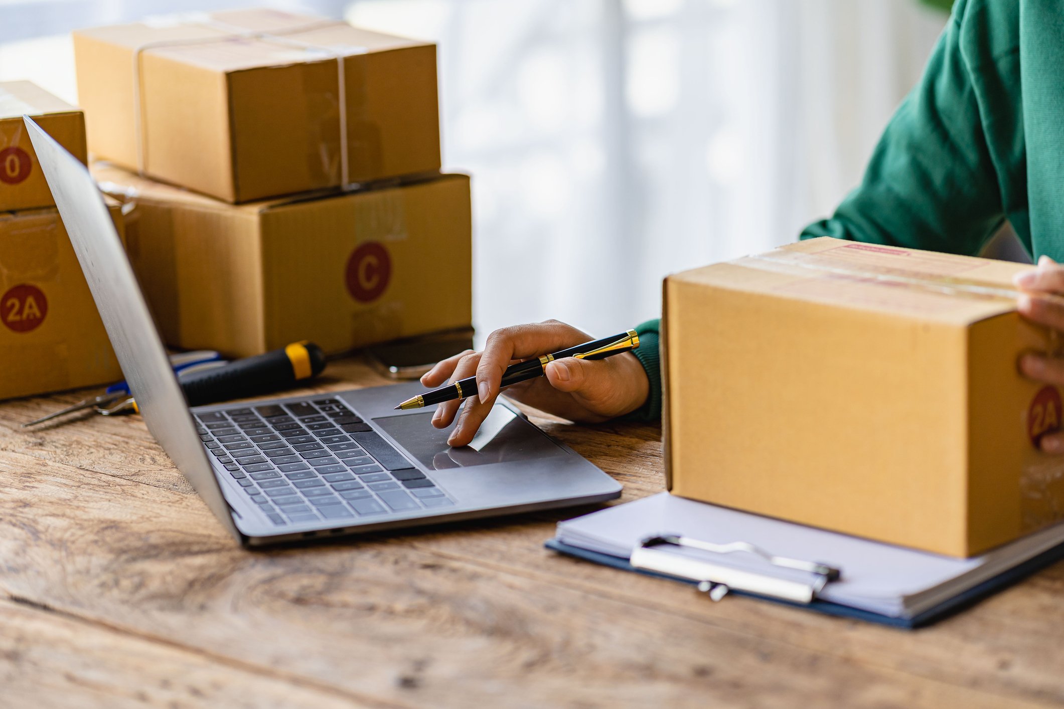 close up of person using laptop with parcels close by