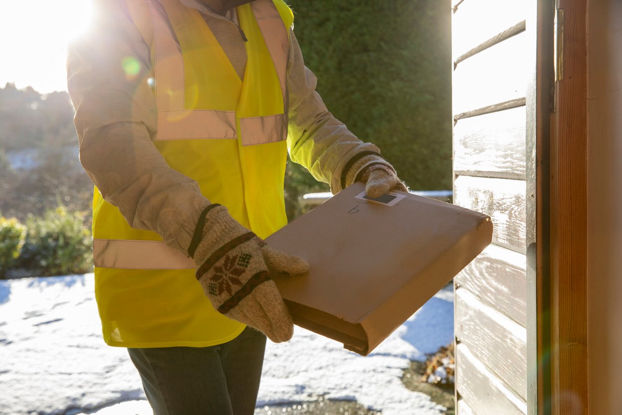 Person in high-vis delivering a box in the snow