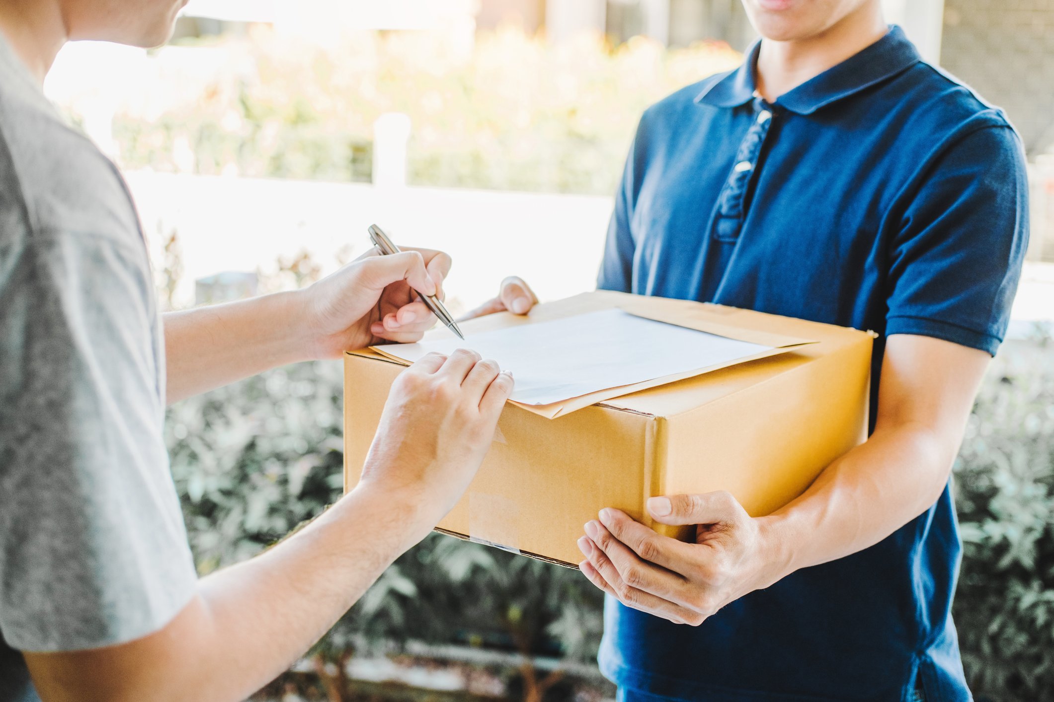 person handing parcel to courier with signing sheet