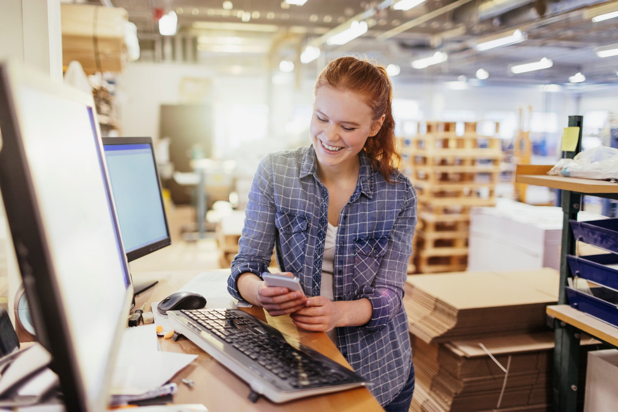 Woman smiling at phone in warehouse