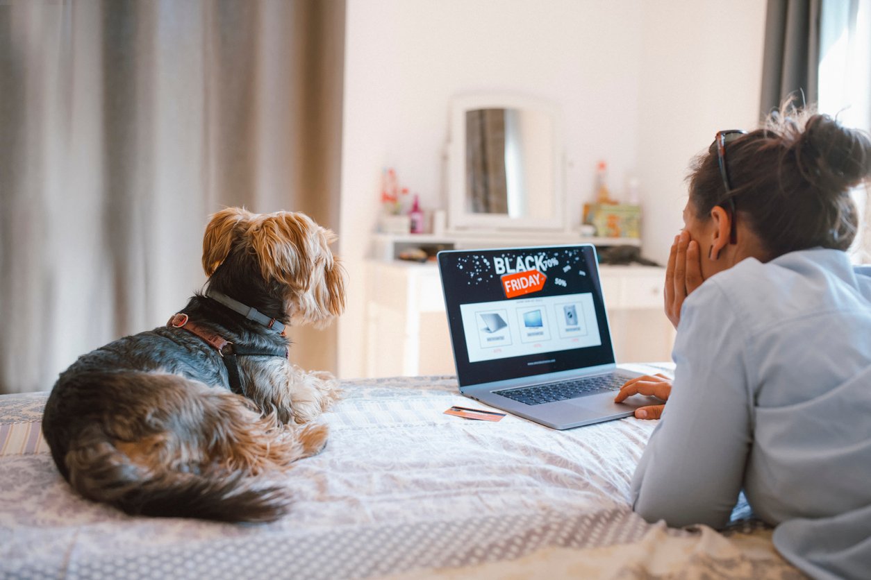 woman-and-dog-on-bed-looking-at-black-friday-laptop