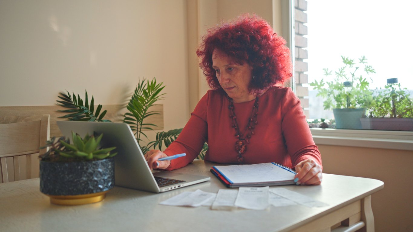 Lady with red hair on laptop organising receipts