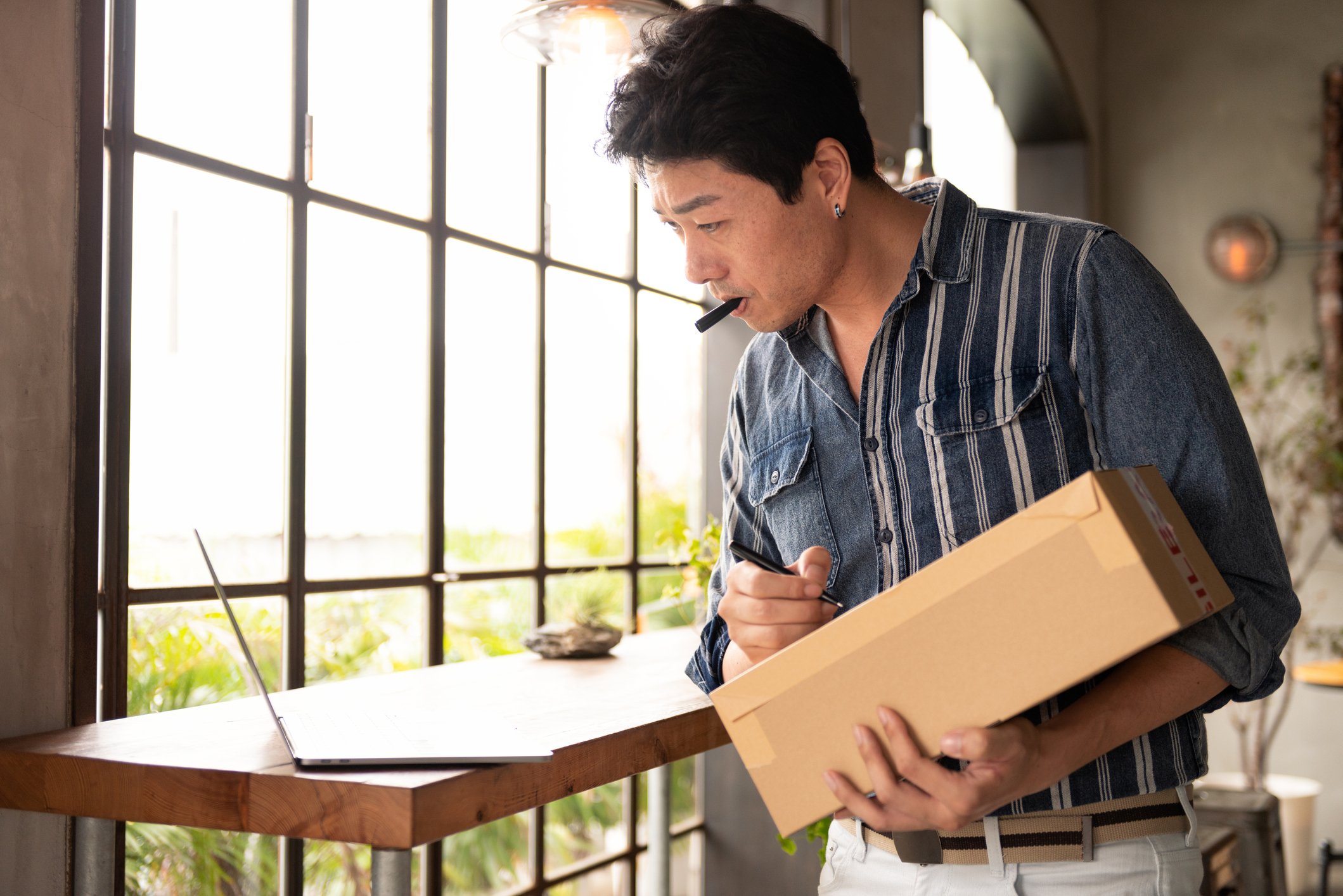 man looking at laptop while writing on parcel