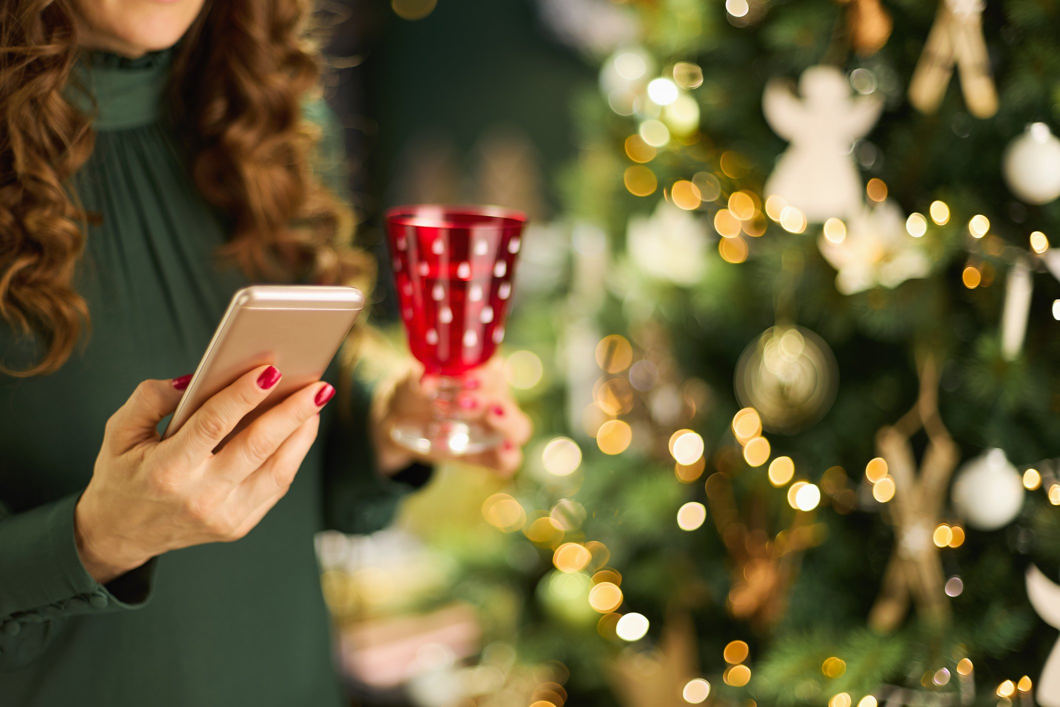 Woman on phone in front of Christmas tree