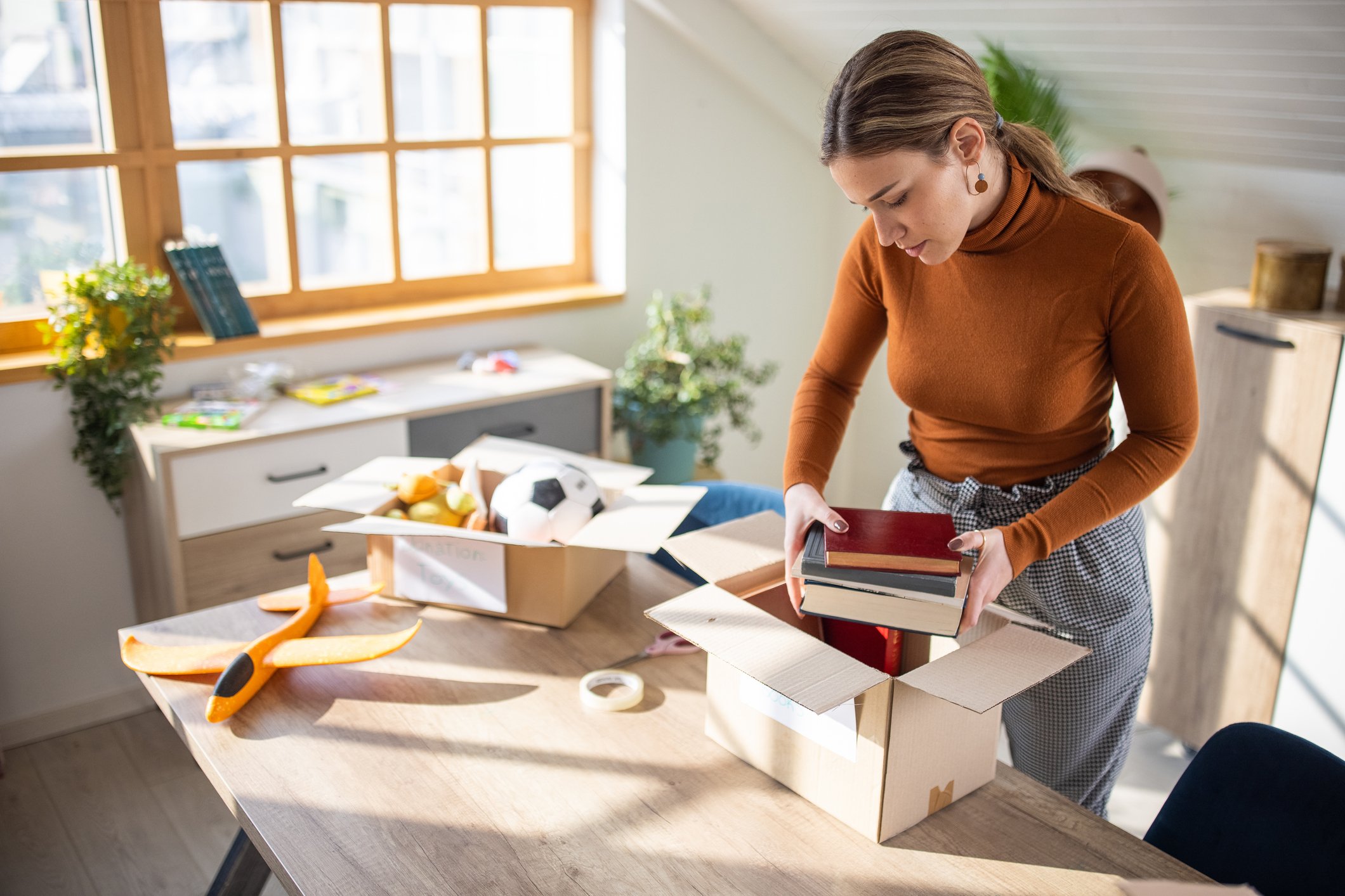 person packing multiple books into parcel