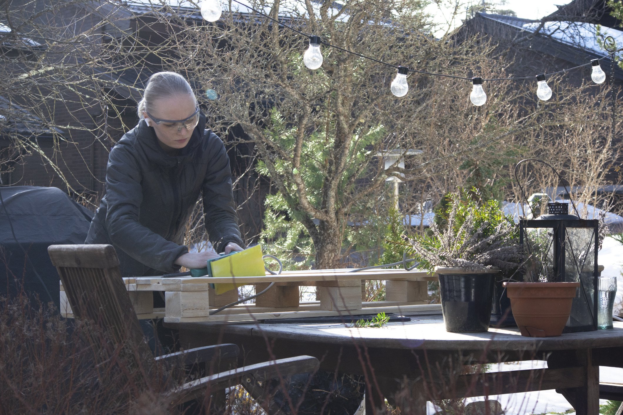 Woman sanding pallet in her garden