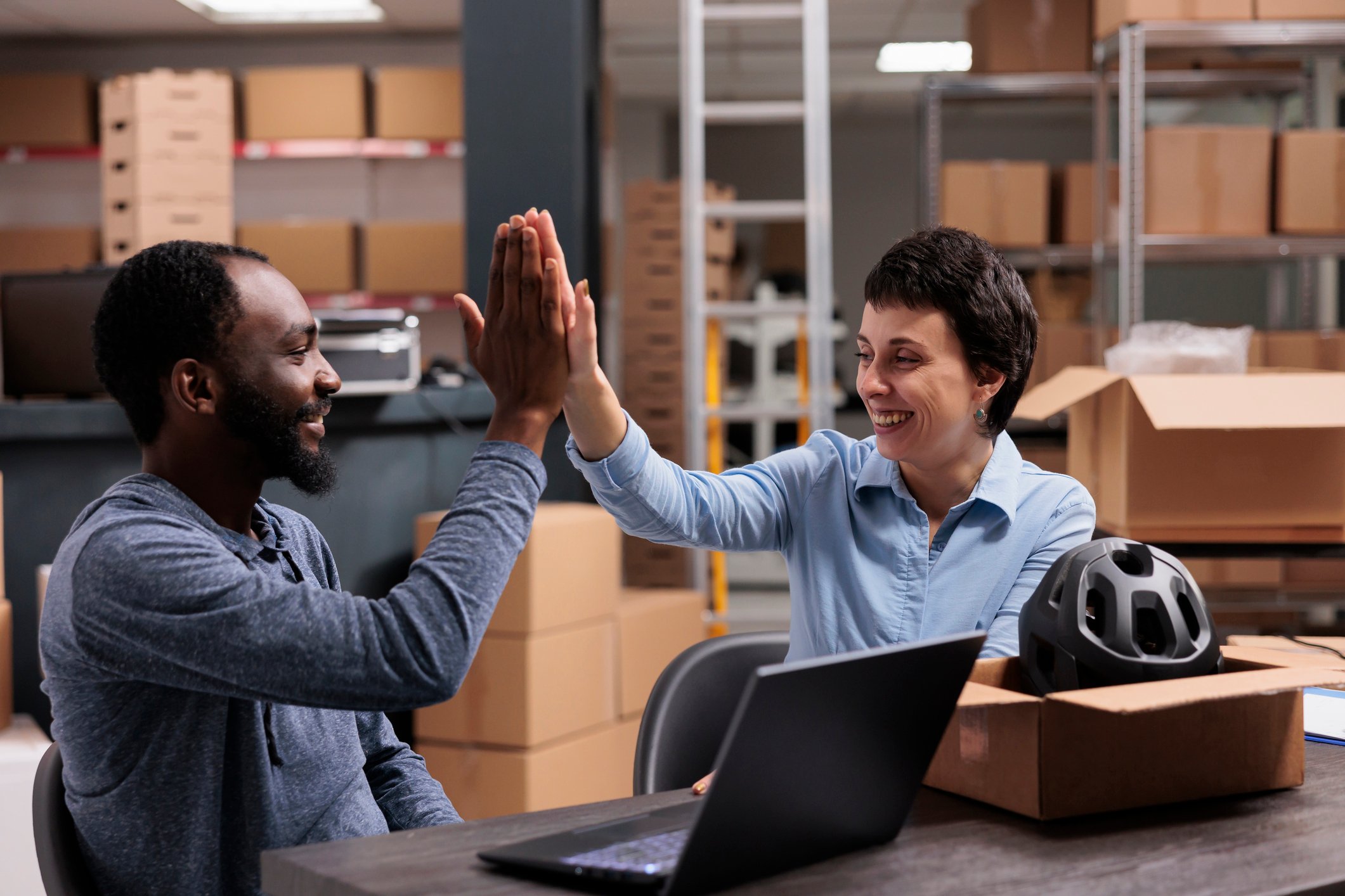 People high five with parcel and laptop on desk
