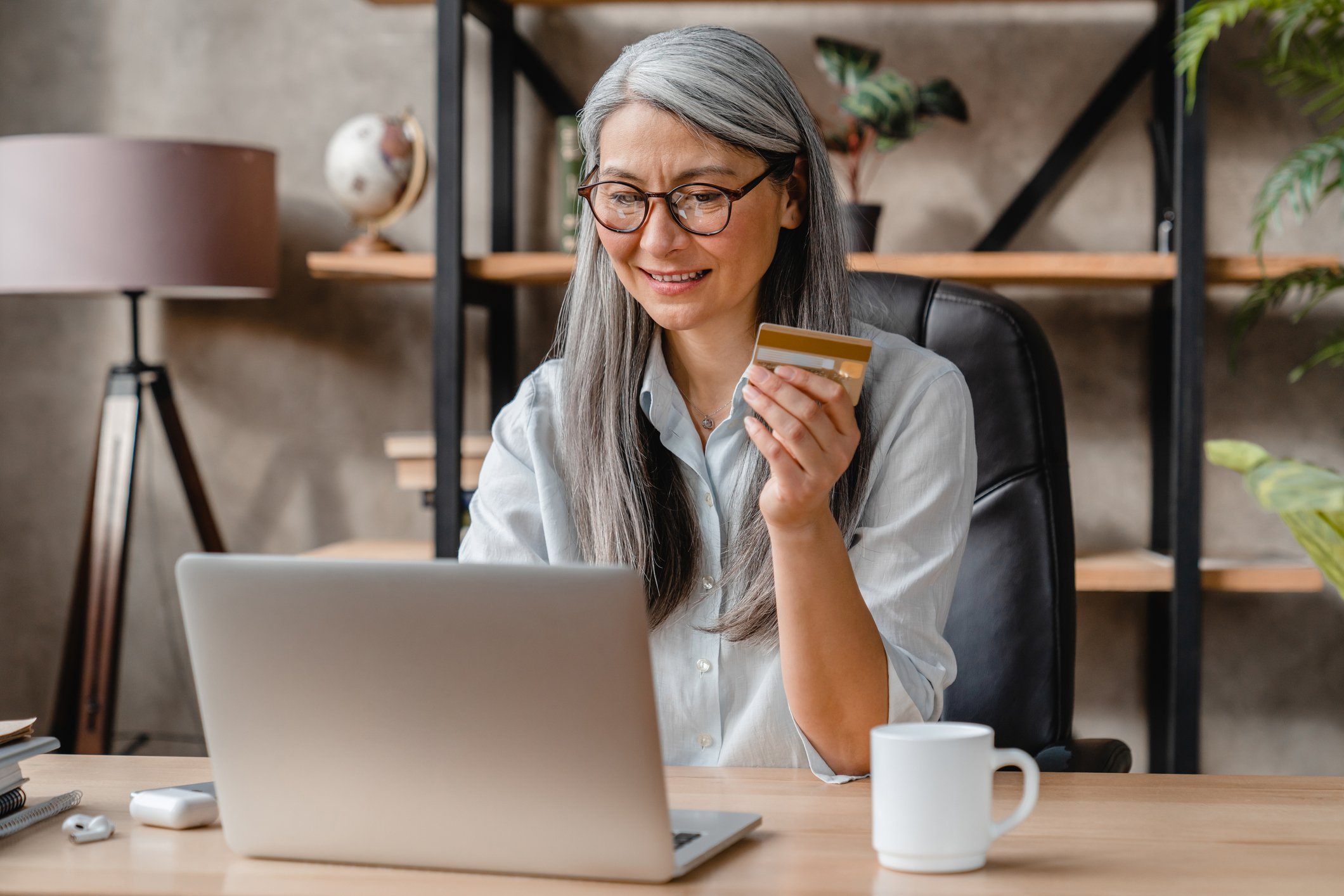 person looking at laptop while holding bank card