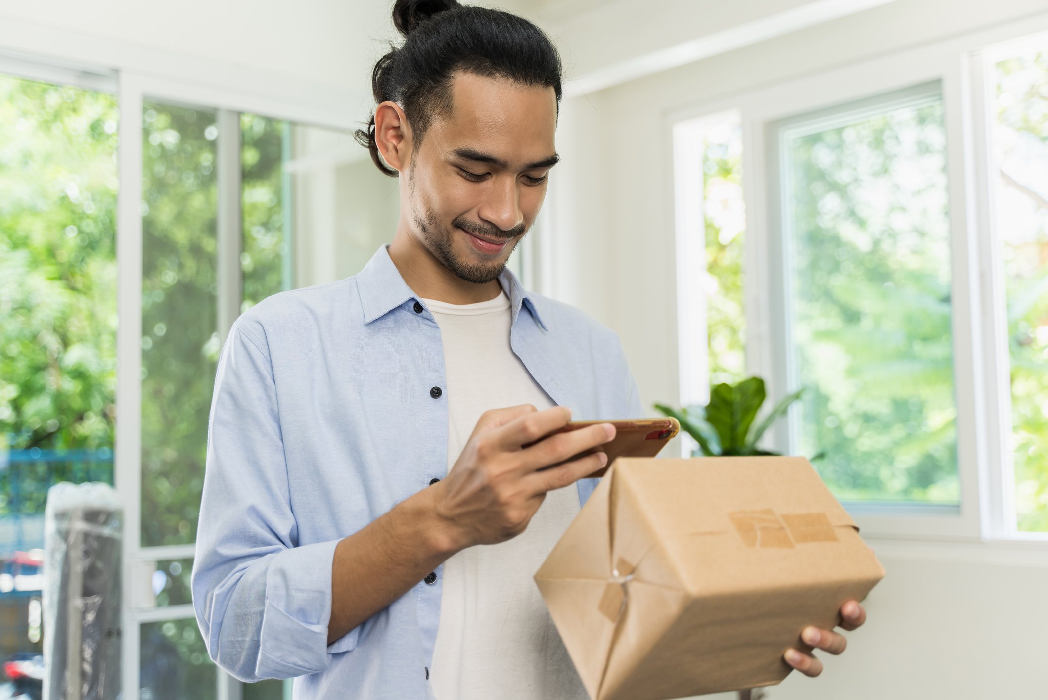 person smiling while looking at phone and parcel