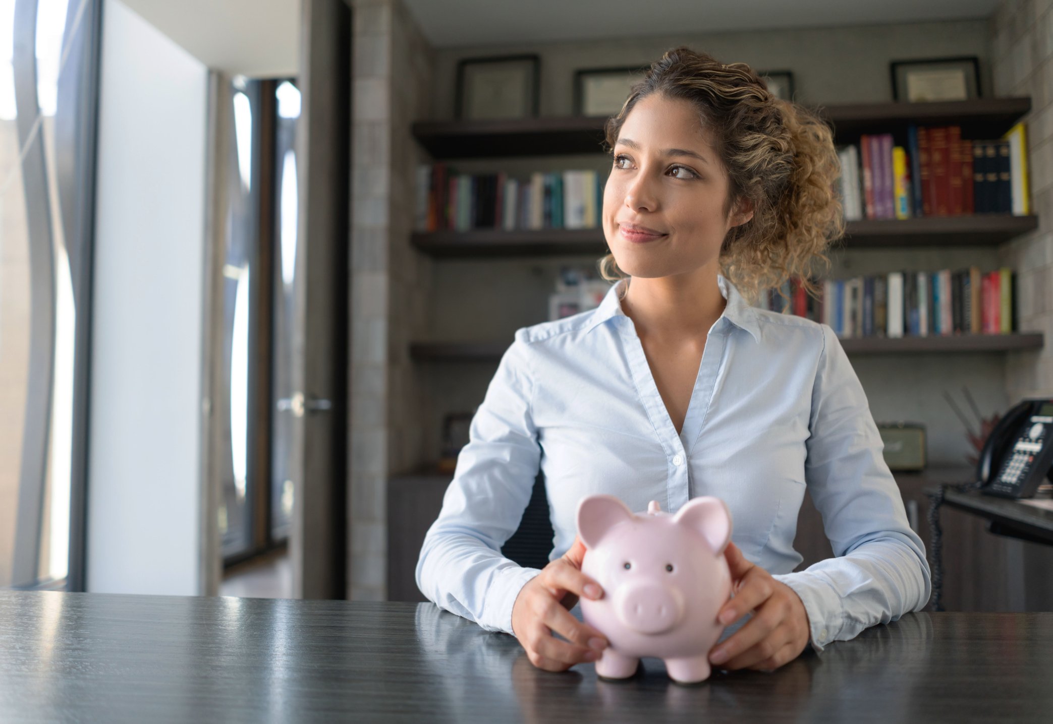 person thinking while holding piggy bank