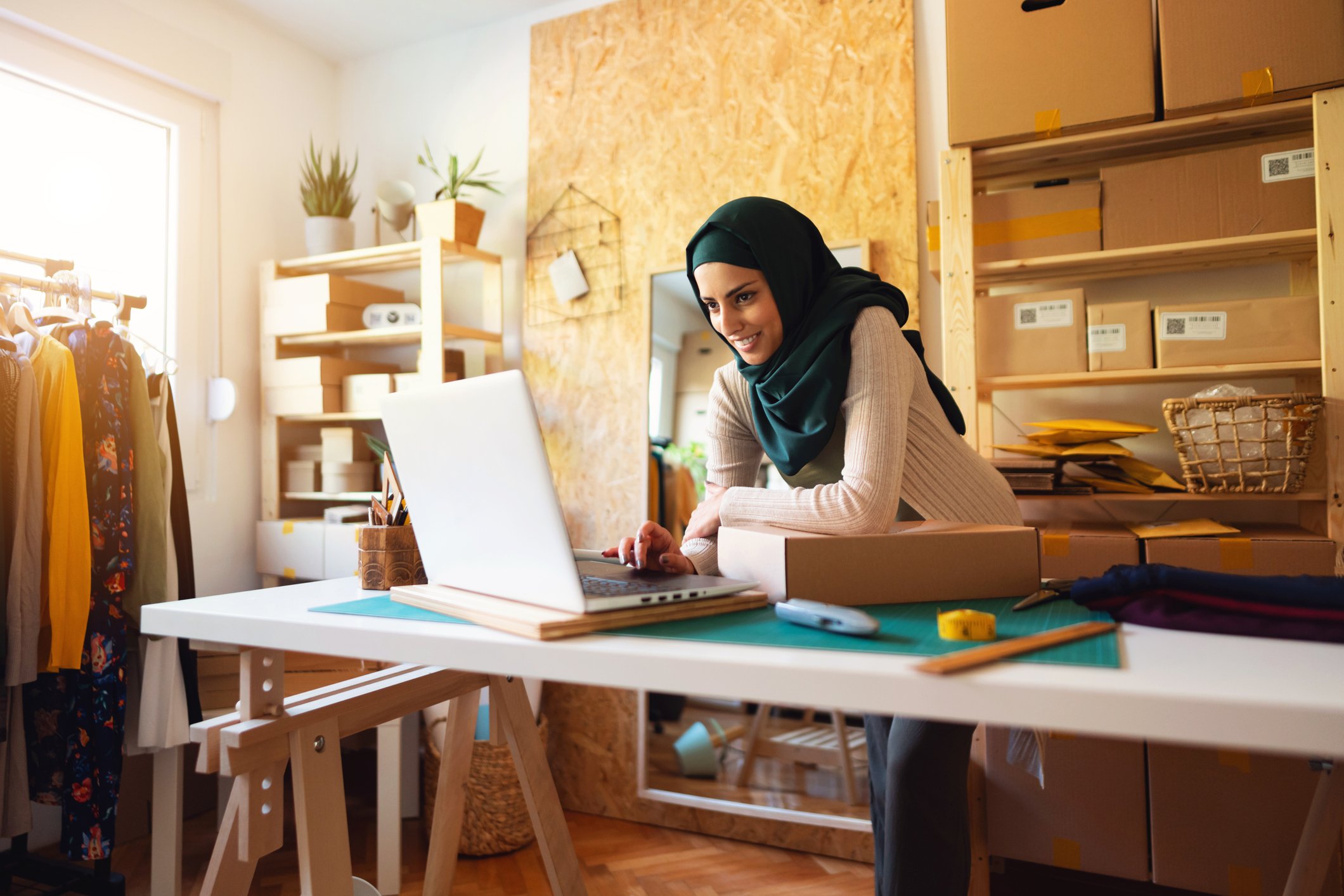 Woman working on laptop surrounded by parcels