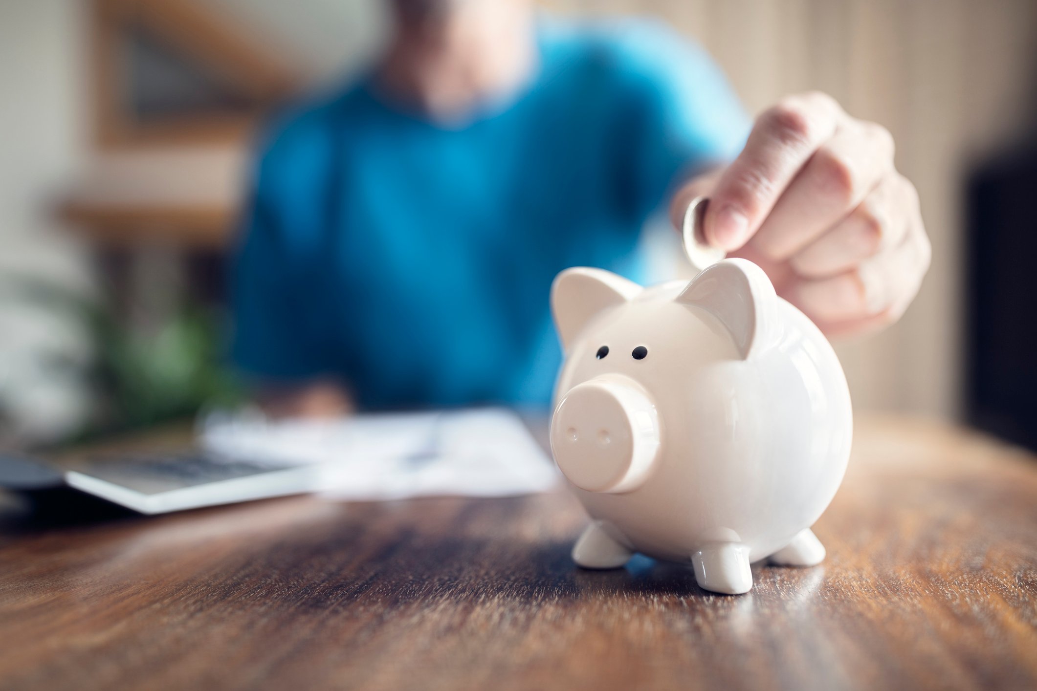 person putting coin into piggybank