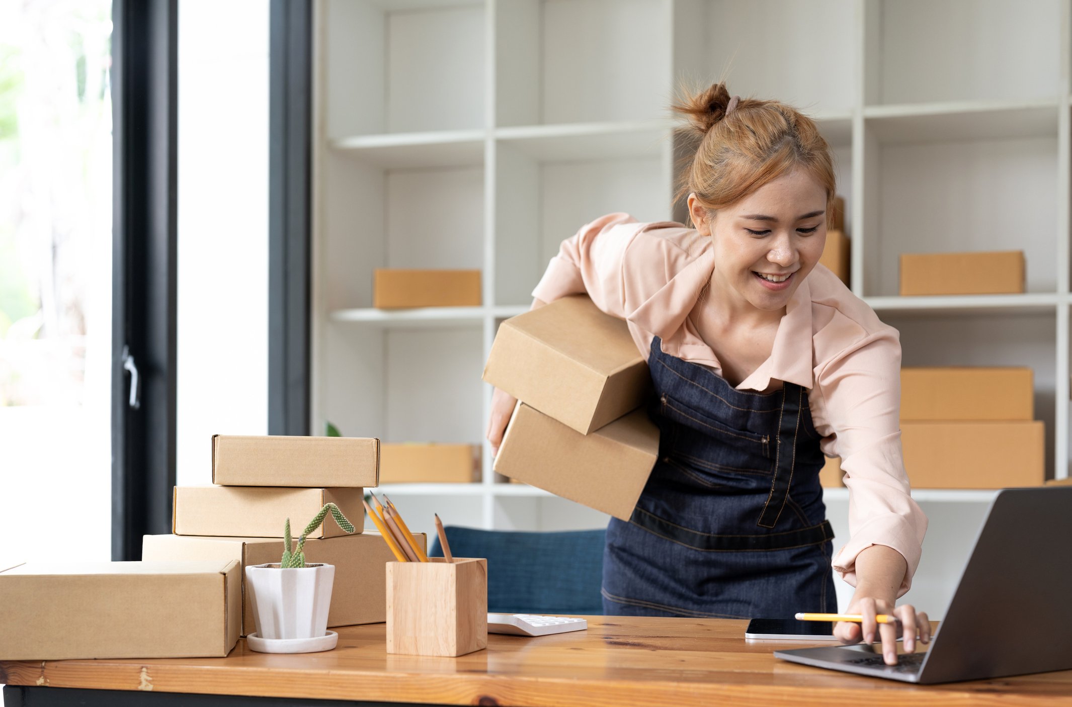 woman holding parcels while on laptop