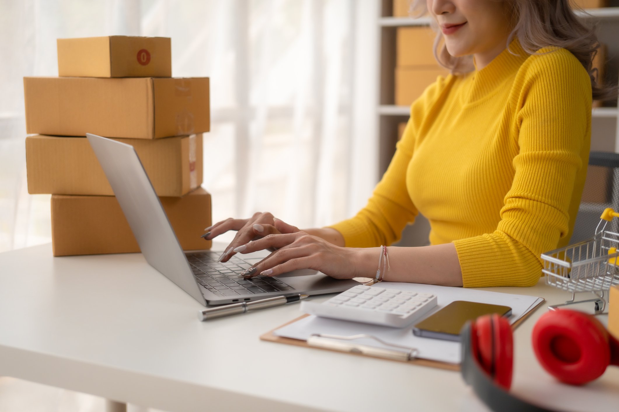 woman-on-laptop-with-parcels-on-desk