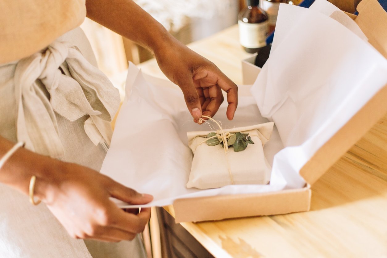 Person wrapping a small parcel in tissue paper in a box