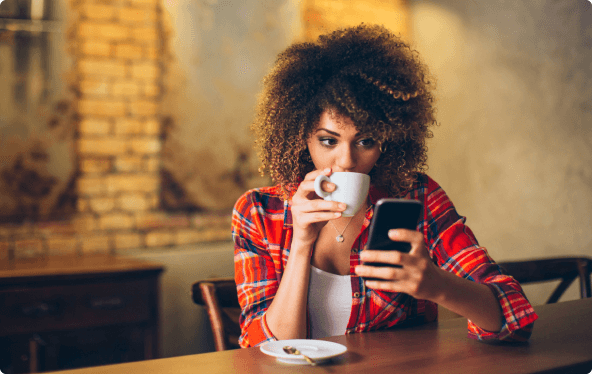 Woman checking phone drinking coffee