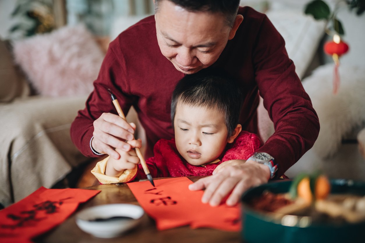 Man and child painting Chinese red envelopes